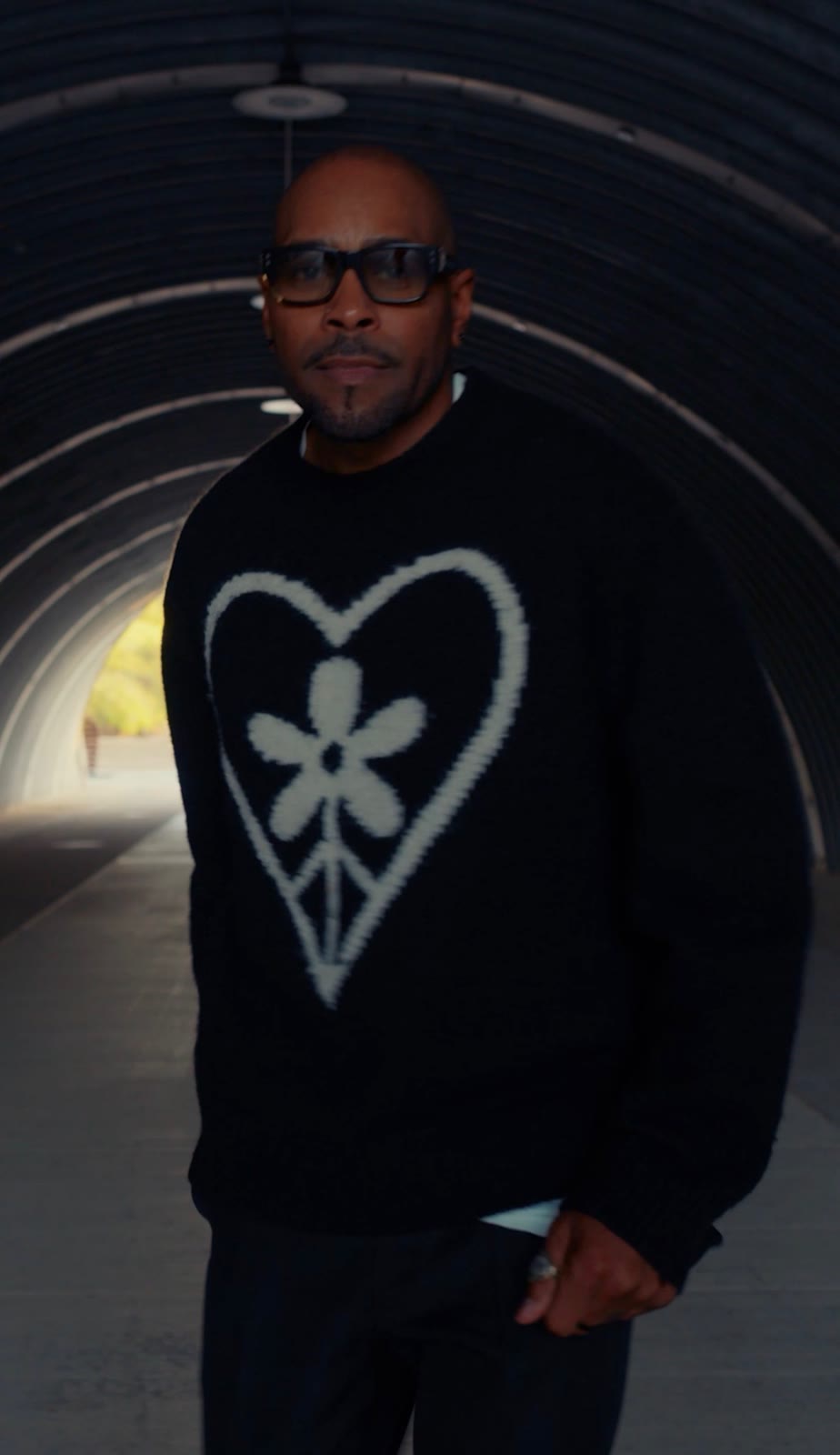 Aaron Skyy close up in the tunnel, heart sweater and dark glasses