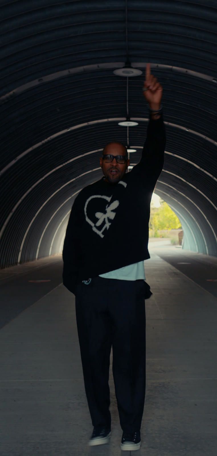 Aaron Skyy pointing skyward in the middle of the tunnel