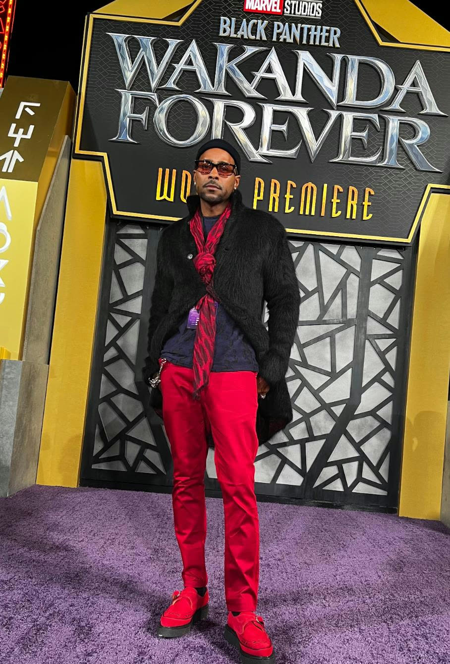 Aaron Skyy in red trousers and a black coat at the Black Panther: Wakanda Forever world premiere