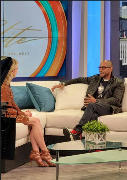 Aaron Skyy seated on a talk-show couch during an interview